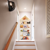 peaked bookshelf creating a focal point at the top of an attic stairway in this refinished attic